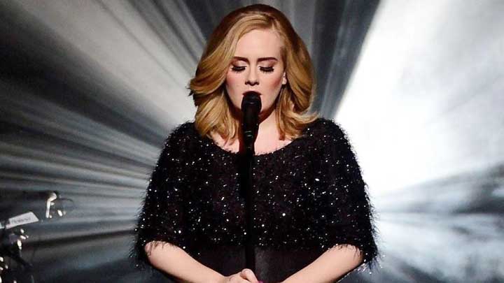 Adele performing on stage in a black dress, showcasing her talent and resilience in managing Generalized Anxiety Disorder.