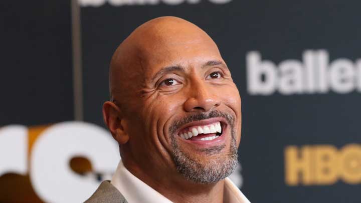 Dwayne Johnson smiling confidently on a function stage, looking straight into the camera, symbolizing his journey of overcoming Major Depressive Disorder.