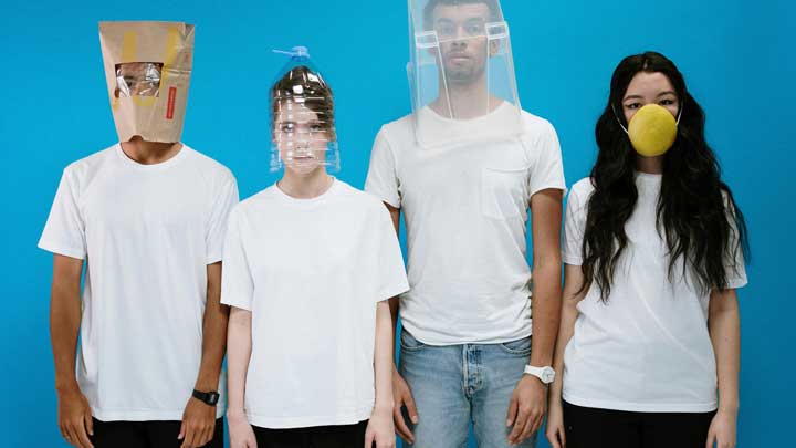 Two young men and two women standing against a blue wall, wearing envelope, jar, and bucket masks, symbolizing the diverse and specific fears associated with Specific Phobias.