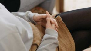 A person sitting cross-legged with fingers interlocked, symbolizing focus and composure amidst the challenges of Tourette Syndrome.