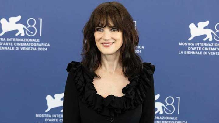 Winona Ryder smiling for the camera in front of a Mostra Internazionale d’Arte Cinematografica banner, symbolizing resilience in overcoming challenges associated with Personality Disorders.